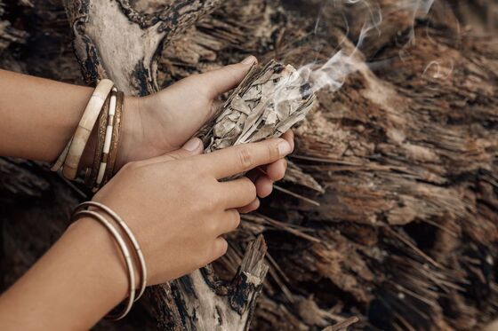 woman holding smudge bundle, sacred herbs, shamanism